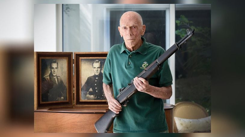Dick Cowell with the rifle and his military portrait. (Photo: Melanie Bell / Palm Beach Daily News)