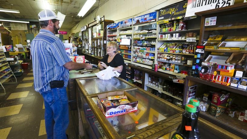 Teresa Jenkins works behind the counter of Tom’s Cigar Store in Hamilton. GREG LYNCH / STAFF