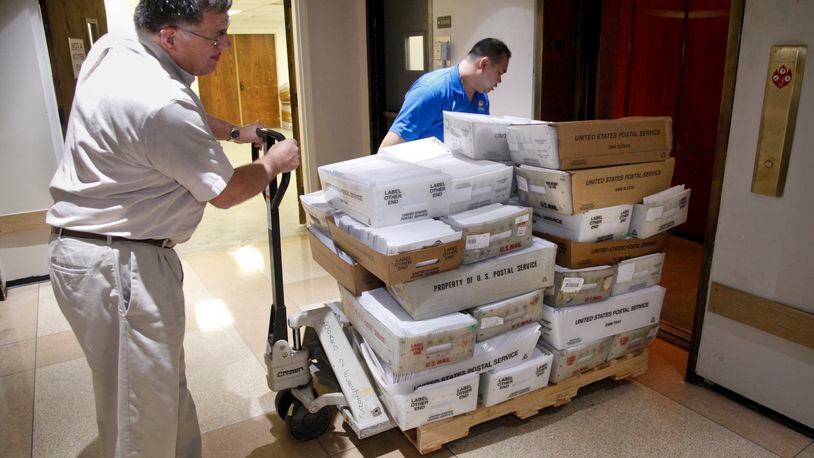 On the first day absentee ballots could be mailed out in 2012, Tim Davis (left), director of mailing services for the Montgomery County Board of Elections and Kim Wong, an IT specialist, transported a load to the mail. LISA POWELL / STAFF