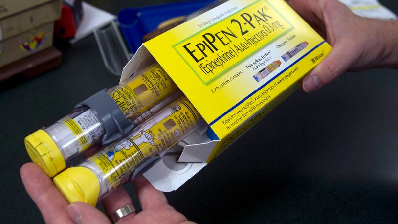 FILE - In this July 8, 2016, file photo, a pharmacist holds a package of EpiPens epinephrine auto-injector, a Mylan product, in Sacramento, Calif. (AP Photo/Rich Pedroncelli, File)