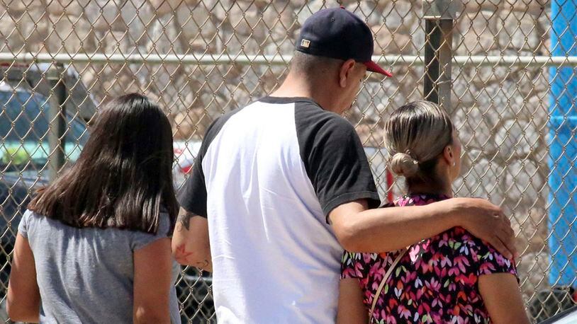 People walk out of an elementary school after family members were asked to reunite following a shooting  at a shopping mall in El Paso, Texas, on Saturday, Aug. 3, 2019.   Multiple people were killed and one person was in custody after a shooter went on a rampage at a shopping mall, police in the Texas border town of El Paso said. (AP Photo/Rudy Gutierrez)