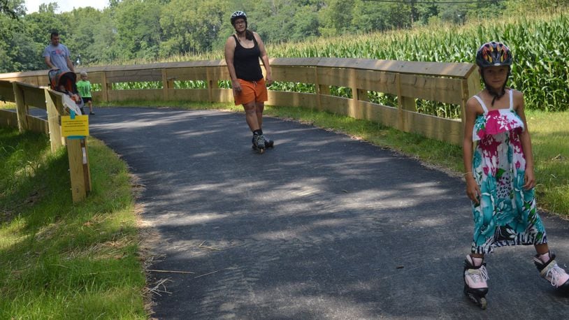 Madison Sparks, right, is followed by her mother, Megan, on the recently-opened section of the Oxford Recreational Trail leaving the Black Covered Bridge. Bill Sparks is at left with a stroller carrying Olivia and holding the hand of Sam. CONTRIBUTED/BOB RATTERMAN