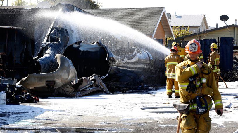 Firefighters douse a fire, which sent up a huge plume of smoke in Los Angeles Sunday, March 17, 2019. Authorities say a 9,000-gallon (34,000-liter) tanker leaking gasoline caught fire and caused an explosion that injured two people in South Los Angeles. The fire department says the blast Sunday morning reverberated through storm drains and sent manhole covers into the air.