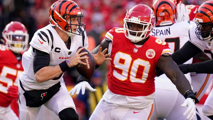 Cincinnati Bengals quarterback Joe Burrow (9) scrambles out of the pocket under pressure from Kansas City Chiefs defensive tackle Jarran Reed (90) during the first half of the AFC championship NFL football game, Sunday, Jan. 30, 2022, in Kansas City, Mo. (AP Photo/Eric Gay)