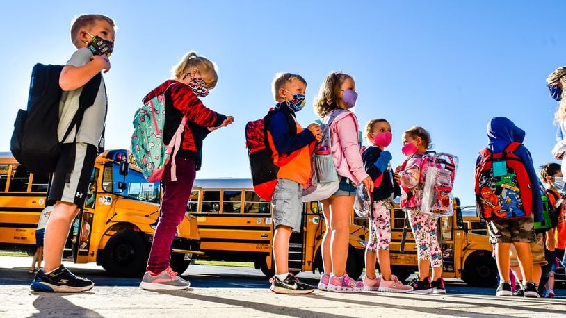 Students wear face masks as they arrive on buses at Madison Elementary School Thursday, August 20, 2020 in Madison Township. NICK GRAHAM / STAFF