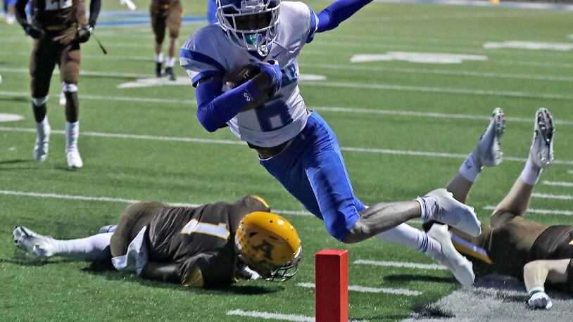 Dunbar's Shaun Huffman dives into the end zone after avoiding tackles from two Alter defenders Friday. BILL LACKEY/STAFF