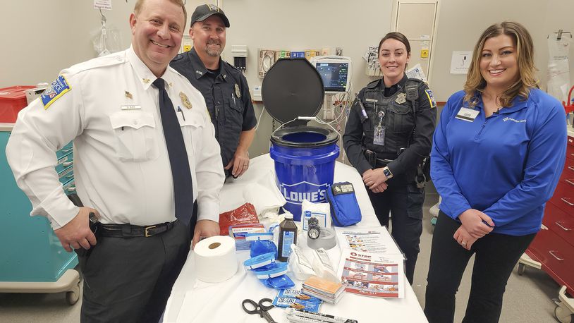 Middletown Division of Police chief David Birk, left, officer Jason Deaton, officer Christine Sorrell Mandi Alcorn, Director of Emergency Trauma Services at Atrium Medical Center, stand with one of the barricade buckets that will be distributed to Middletown school classrooms. Atrium Medical Center and Middletown Division of Police partnered to put emergency kits in Middletown City School district classrooms. Donations from Lowe's, Harbor Freight Tools and Matthew 25: Ministries made it possible to put together 168 buckets with supplies to be used in emergency situations. NICK GRAHAM/STAFF