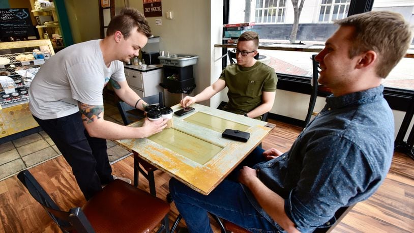 Evan Vossman, left, brings Brad Paynter, middle, and John Monnig their coffee at True West Coffee Downtown on High Street Friday, April 5, 2019 in Hamilton. NICK GRAHAM/STAFF