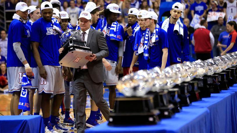 FILE - In this Feb. 22, 2017, file photo, Kansas coach Bill Self carries his 13th Big 12 championship trophy following the team's NCAA college basketball game against TCU in Lawrence, Kan. In the most damaging instance of legal trouble at Kansas this season, police investigated a reported rape at the dorm that houses the basketball team. No charges have been filed. From there, more headlines kept piling up involving no fewer than four players. Self said he's proud his team has rallied despite the steady stream of issues. (AP Photo/Orlin Wagner, File)
