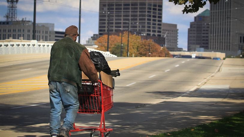 A pedestrian pushes a shopping cart with belongings across the Fourth Street bridge towards the Dayton skyline in 2013. The national poverty rate in 2016 was the lowest since before the recession according to new U.S. Census data. JIM WITMER / STAFF