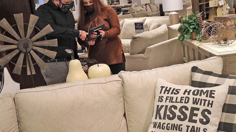 Morris Home Furniture sales professionals David Crist and Michaela Lisch check inventory on a product Friday at Morris' Beavercreek store. BILL LACKEY/STAFF
