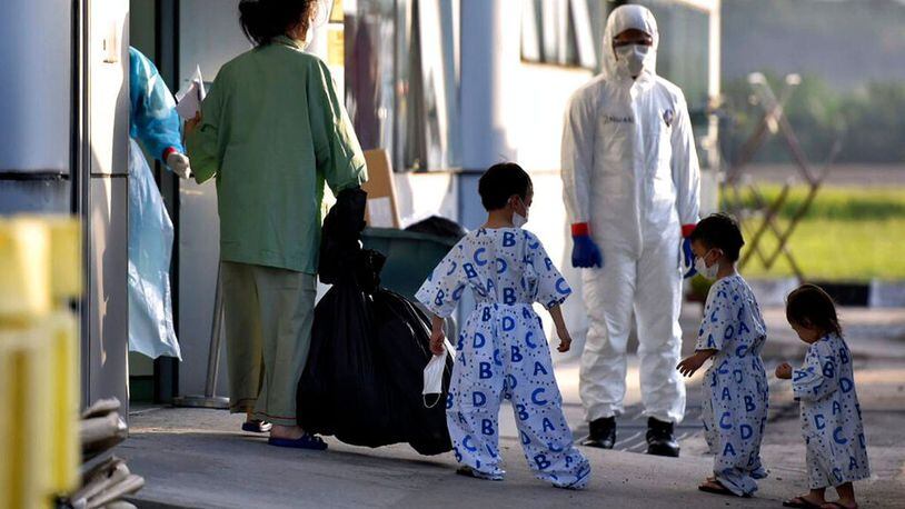 In this photo taken and released by Malaysia's Ministry of Health, a health worker looks at a woman and children arrive at Kuala Lumpur International Airport in Sepang, Malaysia, Wednesday, Feb. 26, 2020, after being evacuated from China's Wuhan, the epicenter of the coronavirus outbreak.
