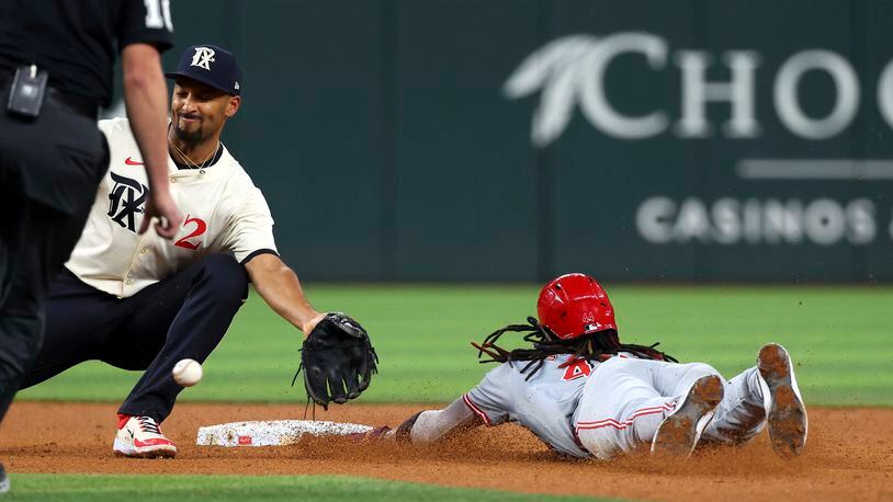Texas Rangers second baseman Marcus Semien (2) gets the ball late as Cincinnati Reds Elly De La Cruz, right, steals second during the fifth inning of a baseball game Friday, April 26, 2024, in Arlington, Texas. (AP Photo/Richard W. Rodriguez)