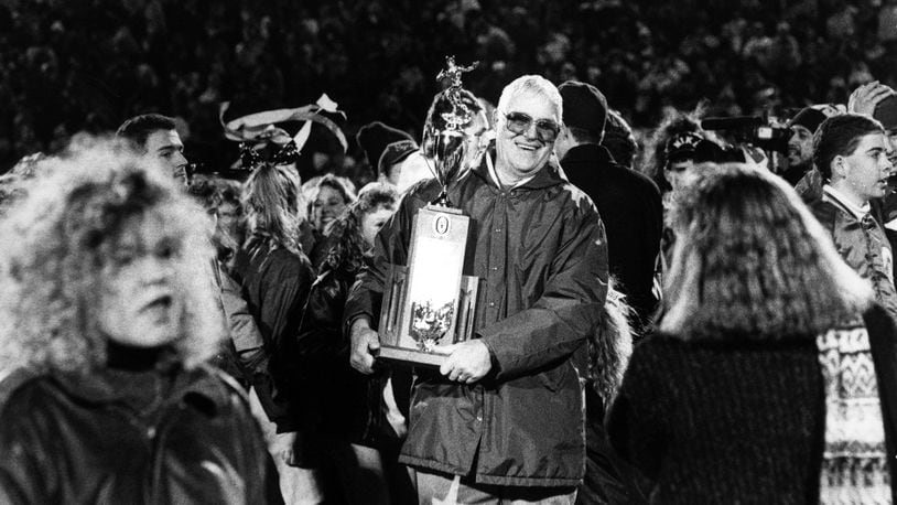 Badin High School football coach Terry Malone happily holds the trophy on Nov. 23, 1990, after the Rams captured the Division III state championship with a 16-6 victory over Richfield Revere at Paul Brown Tiger Stadium in Massillon. JOURNAL-NEWS FILE PHOTO