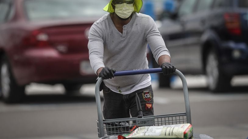 Chris Carlisle of Dayton pushes his cart after shopping at Lowes in Trotwood. Carlisle said he’s concerned about being profiled when he wears his protective mask in public. JIM NOELKER/STAFF