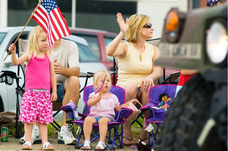 Alyssa McGuire, 3, and Acasia McGuire, 2, wave their American flags as some military vehicles pass by during the Memorial Day Parade Monday morning in Middletown.  Behind the children are Kevin and Jamie McGuire.  NICHOLAS S. GRAHAM
