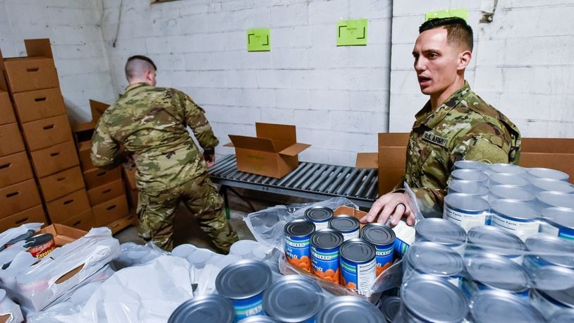 Spc. Seth Bentz, left, and Cpl. Michael Galbreath, members of the Ohio Army National Guard, pack boxes of food at Shared Harvest Food Bank Monday, March 23, 2020 in Fairfield. The Ohio Army National Guard was activated and helped pack food to be distributed to those in need throughout the area. NICK GRAHAM/STAFF