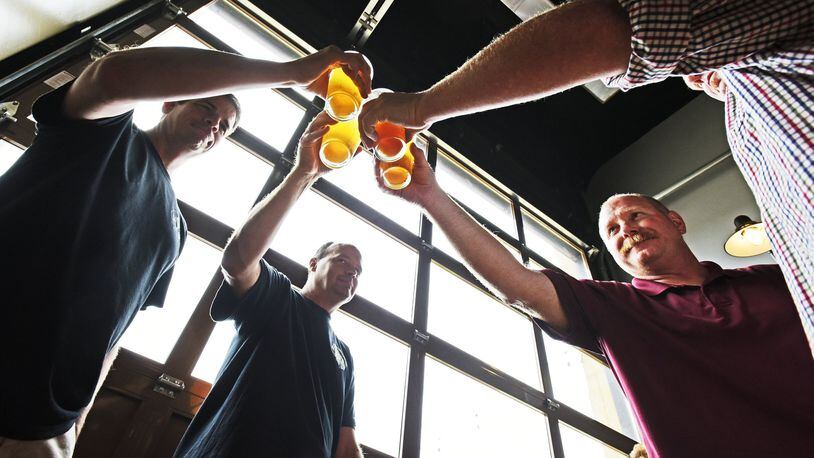 Hamilton’s Municipal Brew Works will again tap its special Woltermelon Blonde Ale to honor fallen firefighter Patrick Wolterman. A ceremonial first pour and toast is set for Aug. 26, according to the brewery’s CEO. Pictured are friends are family of Wolterman during the beer’s 2016 limited release. NICK GRAHAM/2016