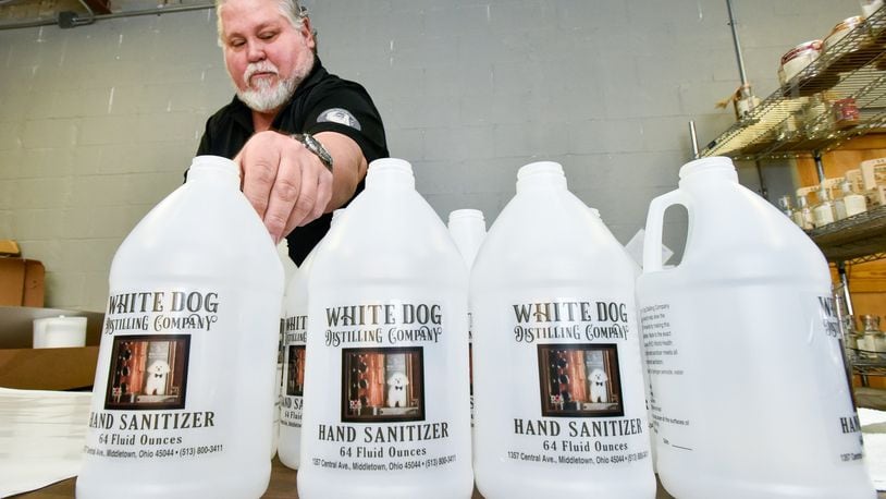 Mike Dranschak puts labels on half gallon jugs that will be filled with hand sanitizer at his Central Avenue business, White Dog Distilling Company, Monday, March 30, 2020 in Middletown. Dranschak has switched from making his usual vodka, rum, gin and agave spirits to producing hand sanitizer during the coronavirus (COVID-19) pandemic. The line in front of his business has extended down the street every day since they started selling the sanitizer. As supplies have been improved in retail stores over the past few months, Dranschak and his wife Debbie, have federal permission to continue to produced hand sanitizer through June. NICK GRAHAM / STAFF