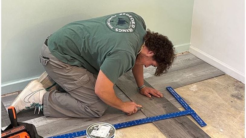 A Service Experience student from Lebanon High School works on new flooring for a room being renovated as part of a shelter for homeless families. ED RICHTER/STAFF