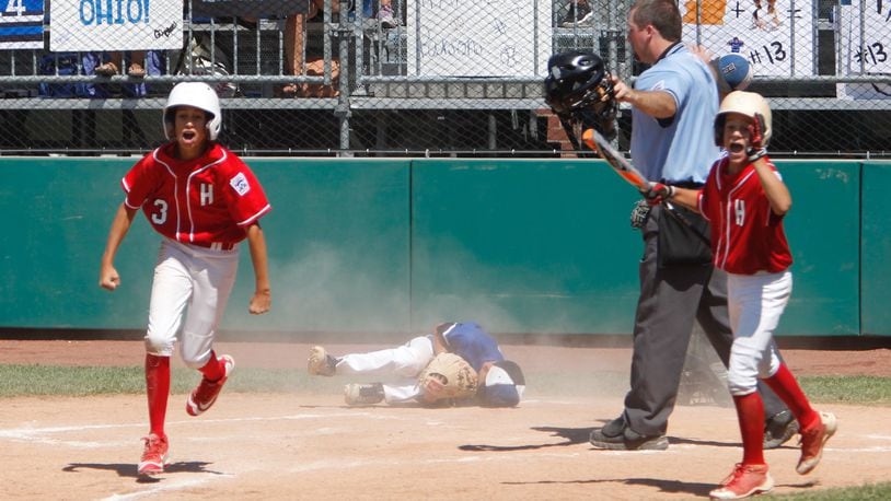 Hinsdale (Ill.) runner Emerson Eck (3) celebrates scoring the winning run on a wild pitch in the bottom of the sixth inning Wednesday as Hamilton West Side suffered a 5-4 defeat in the Little League Great Lakes Regional at Grand Park Sports Campus in Westfield, Ind. That’s West Side pitcher Ethan Mueller on the ground after trying to make the play at the plate. GREG LYNCH/STAFF