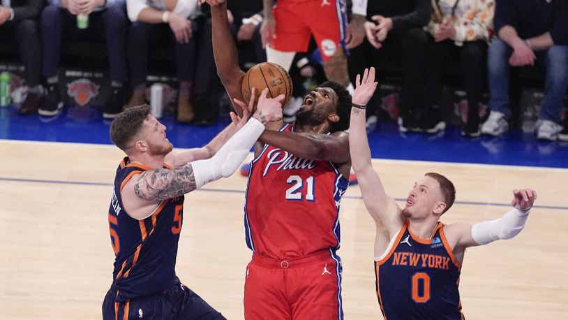 New York Knicks' Isaiah Hartenstein, left, and Donte DiVincenzo, right, defend against Philadelphia 76ers' Joel Embiid (21) during the second half of Game 2 in an NBA basketball first-round playoff series Monday, April 22, 2024, in New York. (AP Photo/Frank Franklin II)