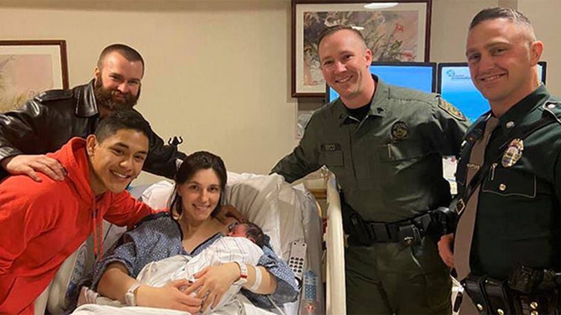 New Hampshire state troopers and a Boscawen police officer pose with baby Dominic and his parents after helping to deliver him early Wednesday, Dec. 25, 2019.