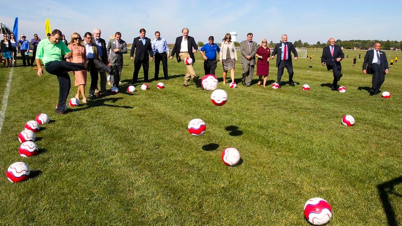 Dignitaries and special guests kick soccer balls as a group during a Grand Opening Ceremony and announcement revealing that West Chester Hospital and the MetroParks of Butler County have a new $1 million partnership to build a shelter house at the Voice Of America Park athletic complex that will house concessions, restrooms, trainer’s rooms, etc. The hospital is donating $1 million over 12 years and will provide sports medicine specialists and physical trainers at no costs to the athletes during tournaments. GREG LYNCH / STAFF