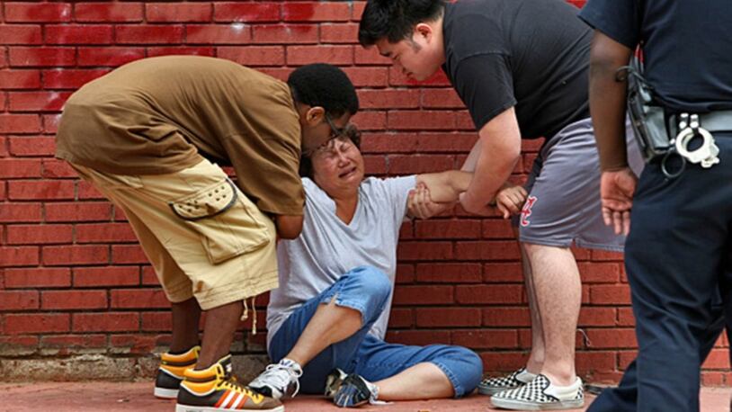 Michael Seagrave (left) and James Sung (right) help a grieving Chae Sung to her feet after she arrived at the store where her husband was killed in 2010.