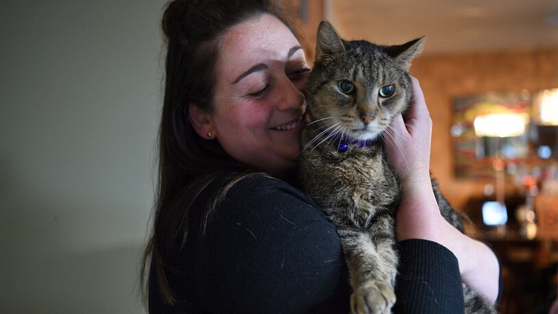 Paige Zelitsky, 23, snuggles with Jimmy, a brown tabby, on Tuesday, April 4, 2017 in Wanaque, N.J.  The cat disappeared after being let out of its Wanaque home on Sept. 13, 2014. The West Milford Animal Shelter Society says Jimmy was found in the town's High Crest section during the March blizzard. (Amy Newman/The Record via AP)