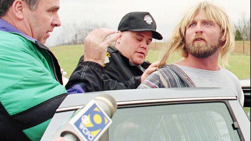 Bob Stephens, left, Kentucky state police detective, and another official put Glenn Rogers in a police cruiser after Rogers was arrested Monday afternoon, Nov. 13, 1995, near rural Waco, Ky. Rogers, 33, is suspected of strangling or stabbing at least four women in California, Louisiana, Mississippi and Florida in the past two months. (AP Photo/The Richmond Register, Phil Poynter)