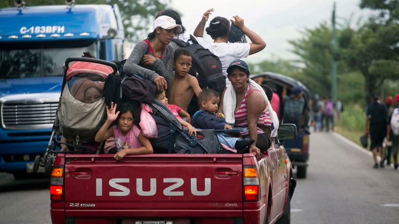 Honduran migrants who are traveling to the U.S. as a group get a free ride in the back of a driver's truck as they make their way through Zacapa, Guatemala, Wednesday, Oct. 17, 2018. The group of some 2,000 Honduran migrants hit the road in Guatemala again Wednesday, hoping to reach the United States despite President Donald Trump's threat to cut off aid to Central American countries that don't stop them. (AP Photo/Moises Castillo)
