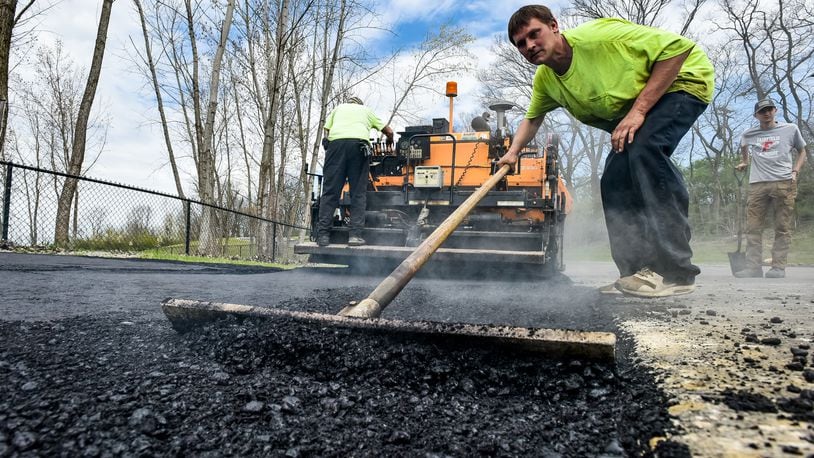 Chase Ditmyer with Barry L. Brown Paving spreads asphalt as they add parking spots at FurField Dog Park Friday, April 3, 2020 in Fairfield. The paving company is working during the coronavirus pandemic and is using the time the park is closed down to get needed parking spots added. NICK GRAHAM / STAFF