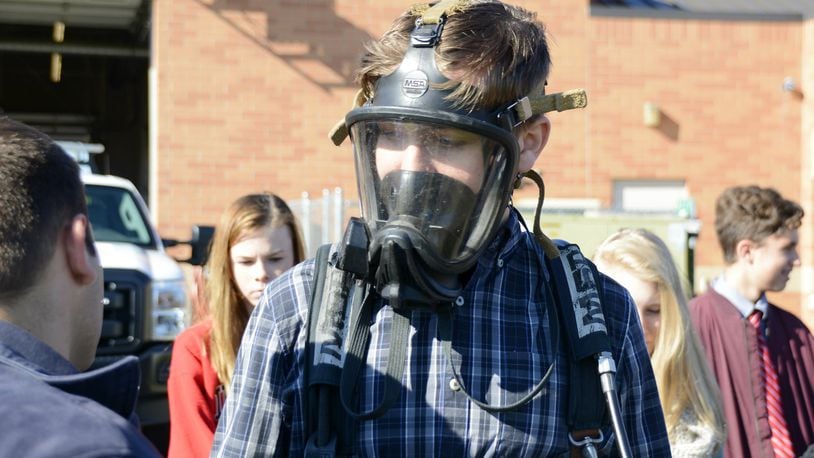 Trent Gleason, a Fairfield freshman, tries on a SCBA mask and tank on Thursday during a career day at the Fairfield Twp. administration building where they learned about township government, including the police and fire departments. Around 200 Fairfield freshmen learned were involved in a career day with Junior Achivement of OKI in various fields out in the community. About 20 visited the Fairfield Twp. Administration offices. MICHAEL D. PITMAN/STAFF