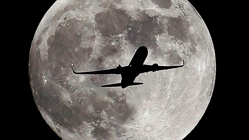 A passenger airliner crosses the full moon, also known as the Hunter's Moon, in Whittier, Calif., on Oct. 7, 2014. (AP Photo/ Nick Ut )