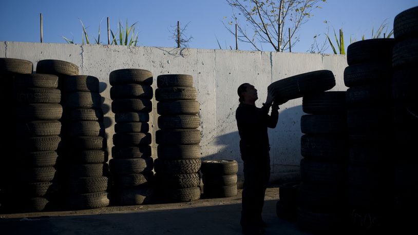 In this Thursday, Nov. 19, 2015, photo, junkyard employee Fabio Flores stacks up used tires at Aadlen Brothers Auto Wrecking, also known as U Pick Parts, in the Sun Valley section of Los Angeles. (AP Photo/Jae C. Hong)