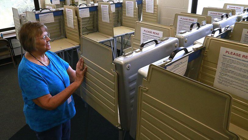 Chris McIntosh, a worker at the Clark County Board of Election, makes sure the voting booths are lined up straight in the early voting/absentee voting room at the board of elections Thursday. BILL LACKEY/STAFF