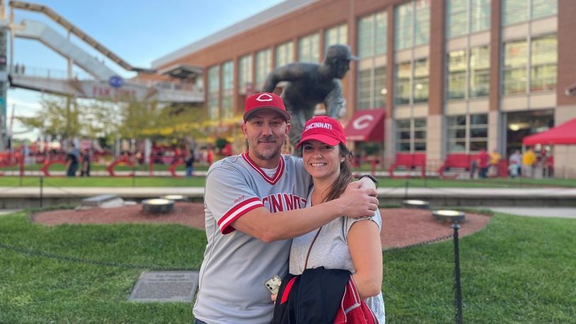 Ben Otto and his wife, Laura, celebrate his walk from their Fairfield home to Great American Ball Park Friday night. He walked 21.5 miles and raised nearly $12,000 for the Joe Nuxhall Miracle League. They posed in front of Nuxhall's statue. SUBMITTED PHOTO