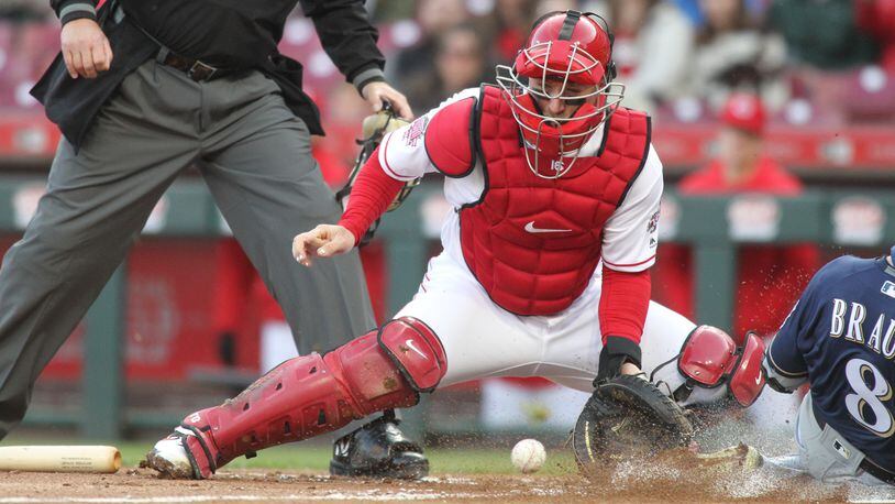 Reds catcher Tucker Barnhart fields a throw as Ryan Braun scores for the Brewers in the first inning on Monday, April 1, 2019, at Great American Ball Park in Cincinnati. David Jablonski/Staff