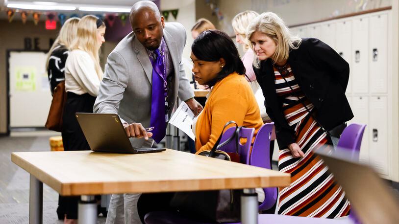 Kee Edwards, left, assistant human resources director for Middletown City Schools, and assistant superintendent Debbie Houser, right, help Jerrica Harris with the job portal process during a job fair for the school district Wednesday, April 13, 2022 at Middletown Middle School. NICK GRAHAM/STAFF