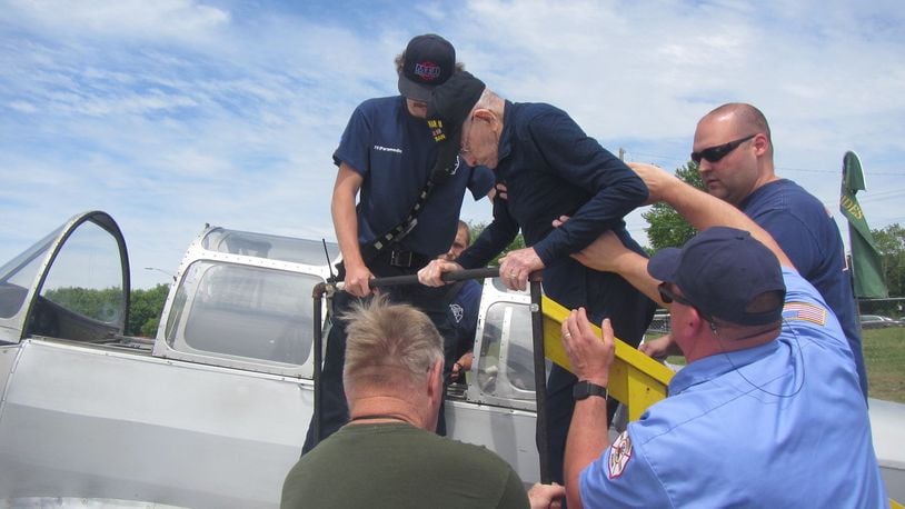 Members of the Middletown Division of Fire help 100-year-old World War II veteran Richard "Dick" Gard climb into a 1943 PT19-A Cornell two-seat warplane Saturday at Middletown Regional Airport. Gard flew with Tim Epperhart, president of the Butler County Warbirds that are based at the Middletown Regional Airport. SUBMITTED PHOTO