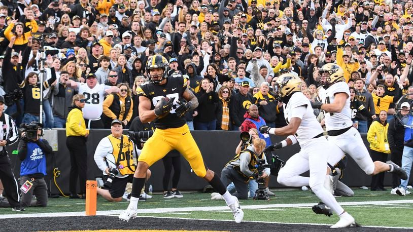 Iowa tight end Erick All (83) pulls in a pass for a touchdown under pressure from Purdue defensive back Markevious Brown (1) and linebacker Yanni Karlaftis (14) during the second half of an NCAA college football game, Saturday, Oct. 7, 2023, in Iowa City, Iowa. (AP Photo/Cliff Jette)