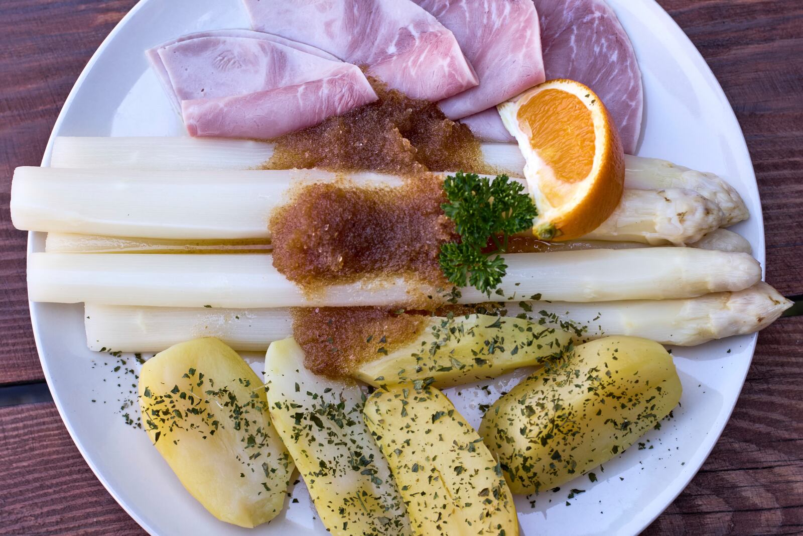 A plate with fresh white asparagus, ham, potatoes and melted butter is served at the Jakobs-Hof farm asparagus restaurant in Beelitz Germany, Thursday, April 3, 2025. (AP Photo/Markus Schreiber)