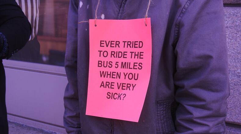A protester holds a sign Tuesday outside the headquarters of Premier Health in downtown Dayton.