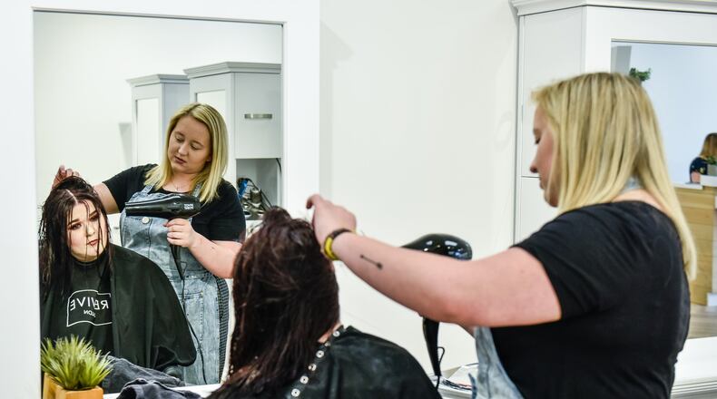Caylin Johnson colors and cuts the hair of Emily Howells at Revive Salon that is now open in The Marcum complex in downtown Hamilton. Revive Salon is the first retail store in the building with Tano’s Bistro, The Casual Pint and several others expected to fill spaces soon. NICK GRAHAM/STAFF