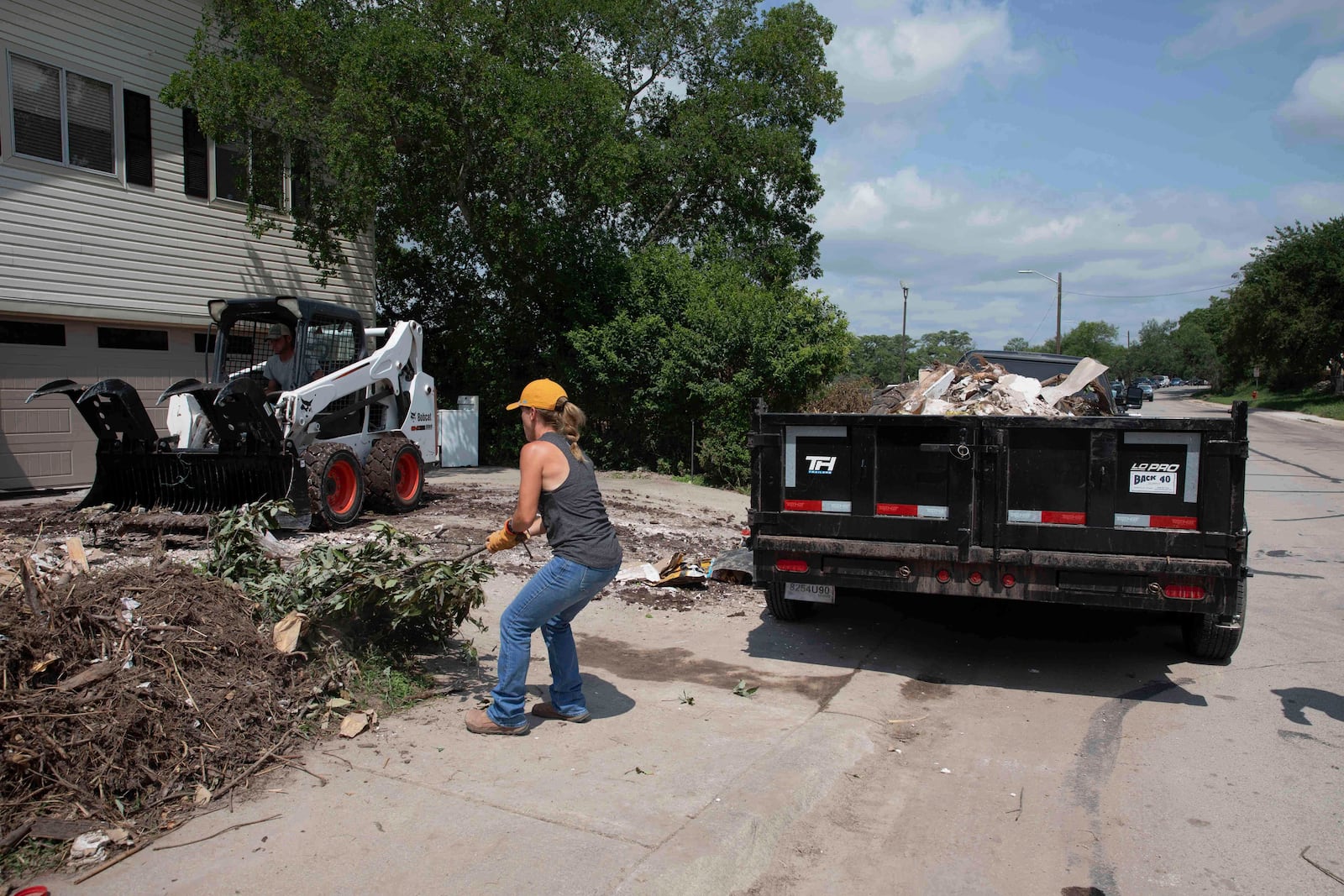 A volunteer removes tree debris from a flood-damaged home on Guadalupe Street in Kerrville, Texas, on July 12, 2025. (AP Photo/Gabriela Aoun Angueira)
