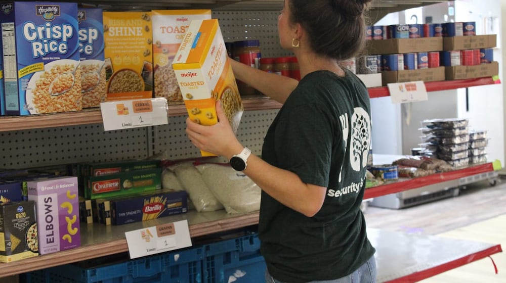 Virginia Willard, a student assistant at the Talawanda Oxford Pantry and Social Services and a senior at Miami University, places food donations on shelves on Nov. 3, 2025. She said, with the influx in need and donations, “there’s just so much more to do all the time,” and numbers of curbside shoppers have nearly doubled. KATELY ALUISE?OXFORD FREE PRESS