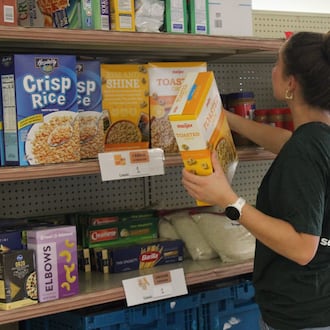 Virginia Willard, a student assistant at the Talawanda Oxford Pantry and Social Services and a senior at Miami University, places food donations on shelves on Nov. 3, 2025. She said, with the influx in need and donations, “there’s just so much more to do all the time,” and numbers of curbside shoppers have nearly doubled. KATELY ALUISE?OXFORD FREE PRESS