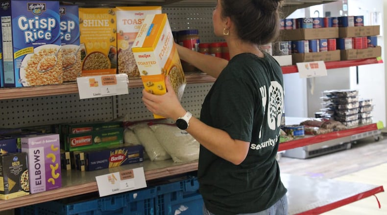 Virginia Willard, a student assistant at the Talawanda Oxford Pantry and Social Services and a senior at Miami University, places food donations on shelves on Nov. 3, 2025. She said, with the influx in need and donations, “there’s just so much more to do all the time,” and numbers of curbside shoppers have nearly doubled. KATELY ALUISE?OXFORD FREE PRESS