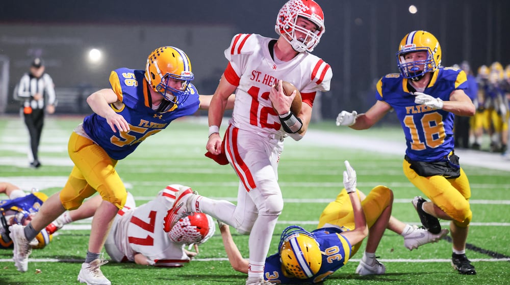 St. Henry senior quarterback Charlie Werling runs as Marion Local's Jacob Muhlenkamp tries to tackle during a touchdown run late in the second quarter of a Division VII, Region 28 championship on Friday, Nov. 21 at Mercy Health/Wapak VFW Field in Wapakoneta. BRYANT BILLING/STAFF
